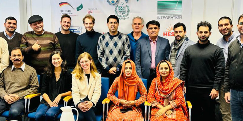 Das Bild zeigt die pakistanische Delegation gemeinsam mit den RLI Expert*innen für ein Gruppenbild aufgestellt, im Hintergrund ein Plakat mit Logos